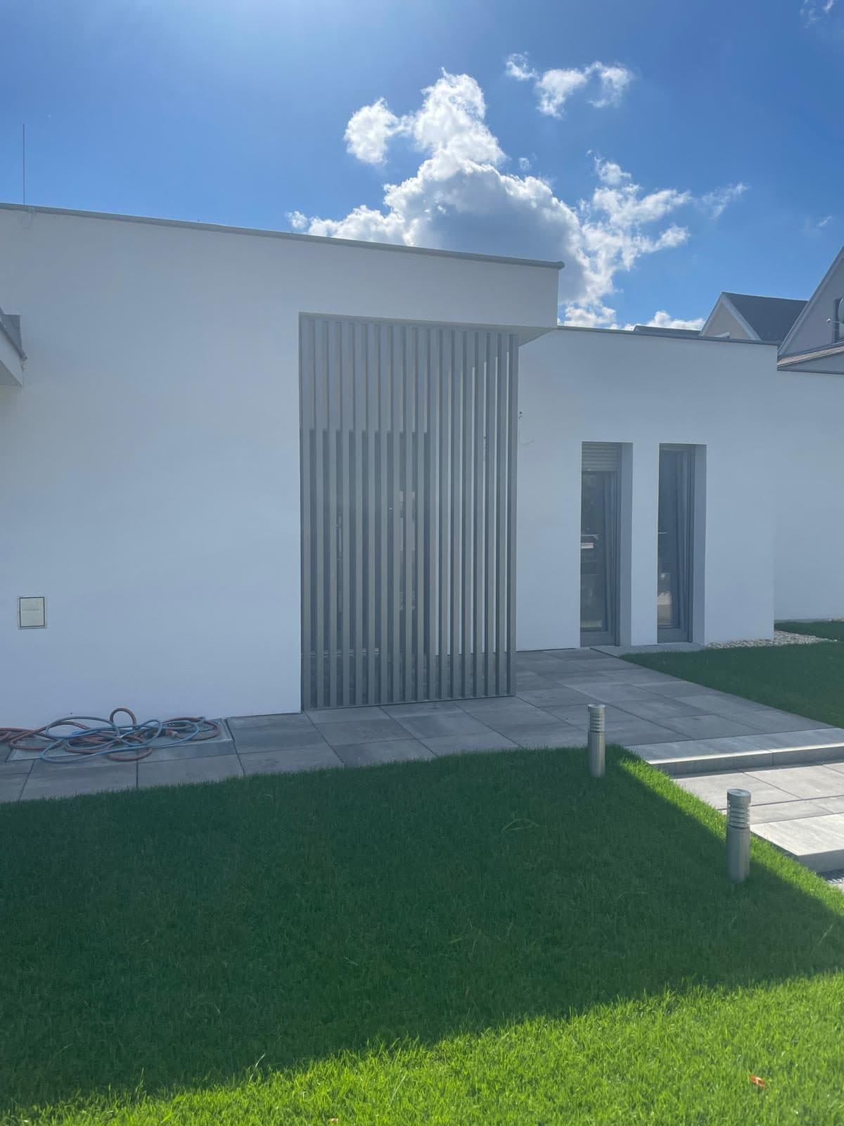 Vertikale Aluminiumlamellen als Sicht- und Sonnenschutz an einer weißen Fassade