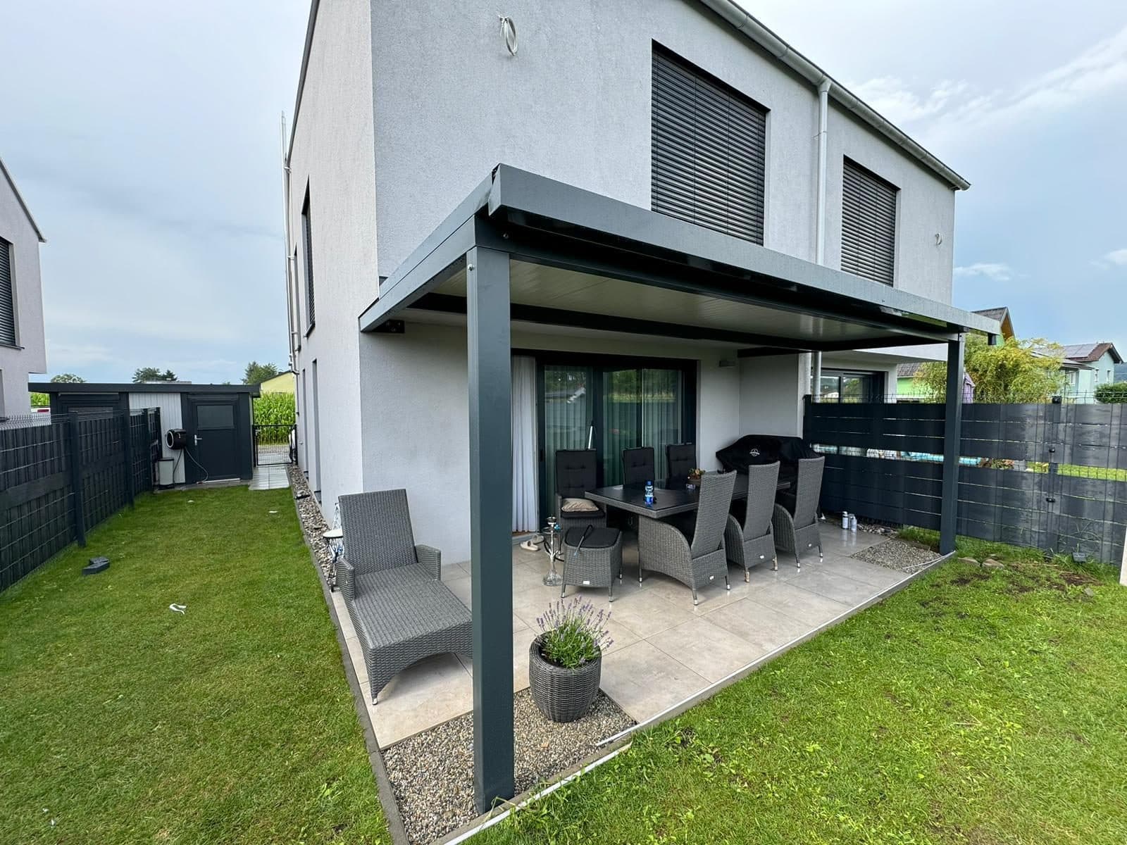 Anthrazitfarbene Terrassenüberdachung an einem modernen Doppelhaus