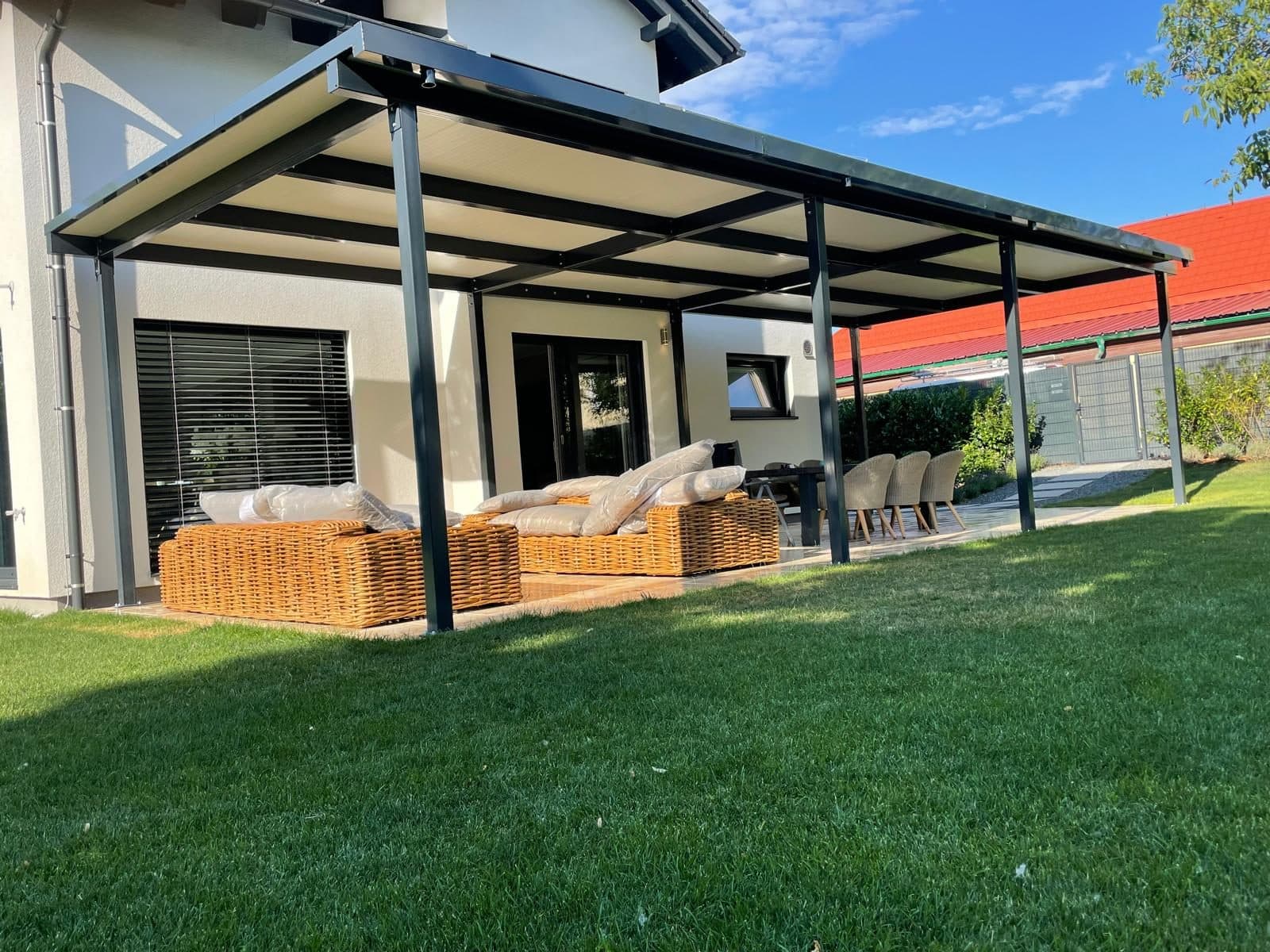 Von AM Outdoor Solutions montierte Terrassenüberdachung in Anthrazit über einer Lounge-Terrasse