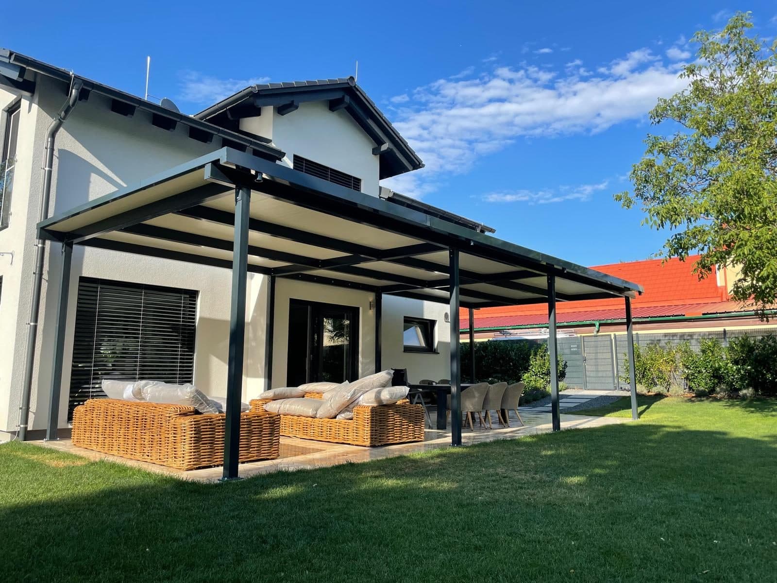 Anthrazitfarbene Terrassenüberdachung über einer Lounge-Terrasse im Garten
